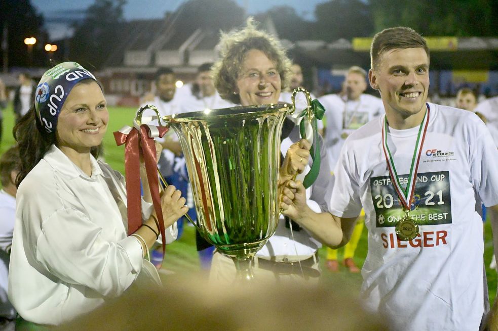Den Siegerpokal nahm Kickers-Kapitän Bastian Dassel am Freitag von zwei Frauen entgegen. Die Bundestagsabgeordnete Gitta Connemann (links) und die Leeraner Bürgermeisterin Beatrix Kuhl übergaben den Pott. Fotos: Damm