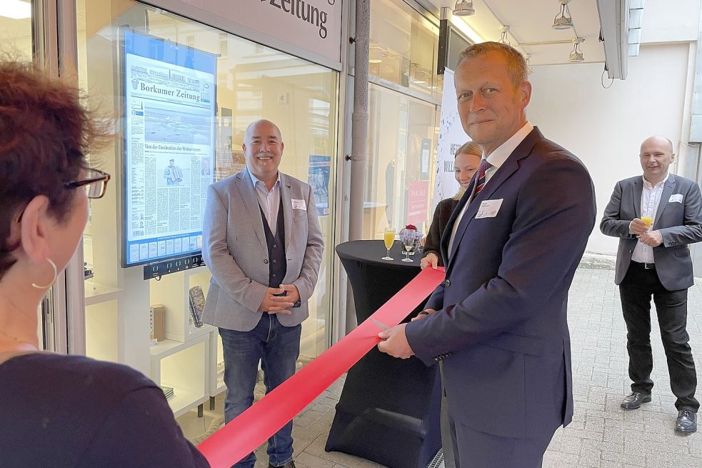 Bürgermeister Jürgen Akkermann durchschnitt das rote Band und eröffnete unter den Augen von Verleger Robert Dunkmann die neue Geschäftsstelle der Borkumer Zeitung. Foto: Nording