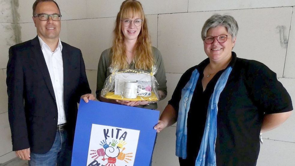 Lena Wessels (MItte) hat das Logo der neuen Kita "Rundum" in Westerhusen gezeichnet. Ihr Entwurf wurde unter 22 Einsendungen ausgewählt. Ein kleines präsent überreichten Sascha Ukena (Gemeinde Hinte, links) und Dagmar Wacker (Kita-Leiterin). Foto: Gemeinde Hinte