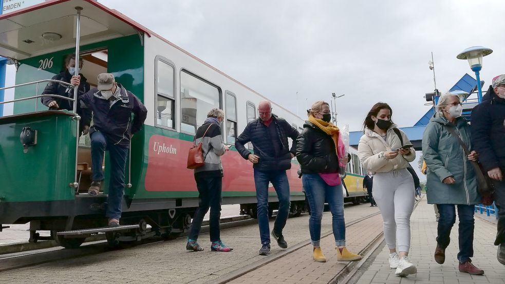 Urlauber verlassen am Borkumer Hafen die Kleinbahn, um auf die Fähre nach Emden überzusetzen. Foto: Kraft