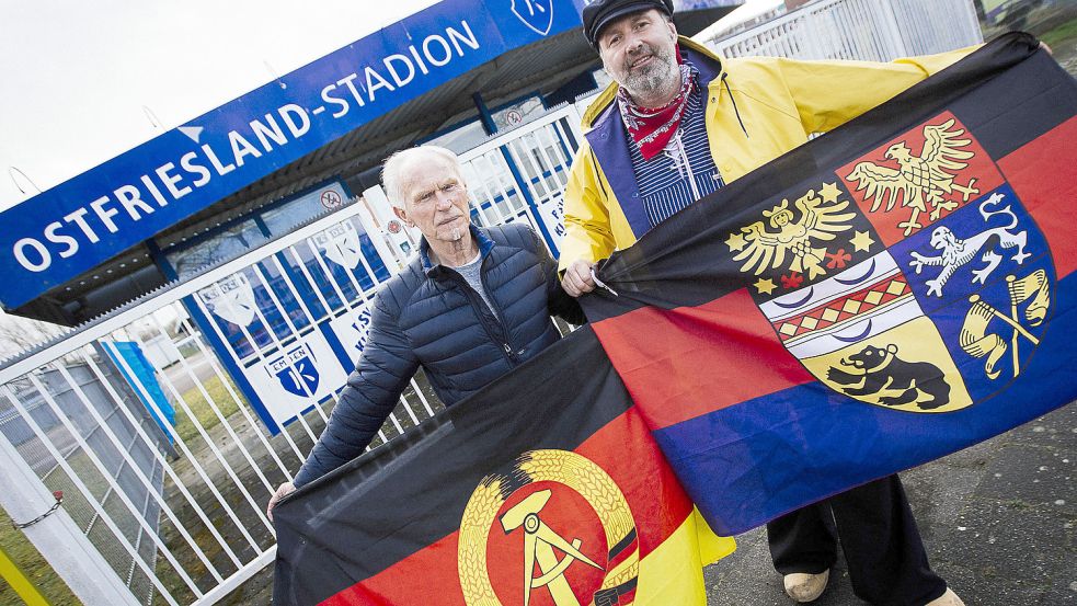 Vor rund einem halben Jahr machte der Emder Kai Schoolmann (rechts) seine „Länderspiel“-Pläne öffentlich und posierte mit dem „DDR-Teamchef“ Helmut Schühler (links, früher Hansa Rostock) und den „Nationalfahnen“ vor dem Emder Ostfrieslandstadion. Archivfoto: Doden