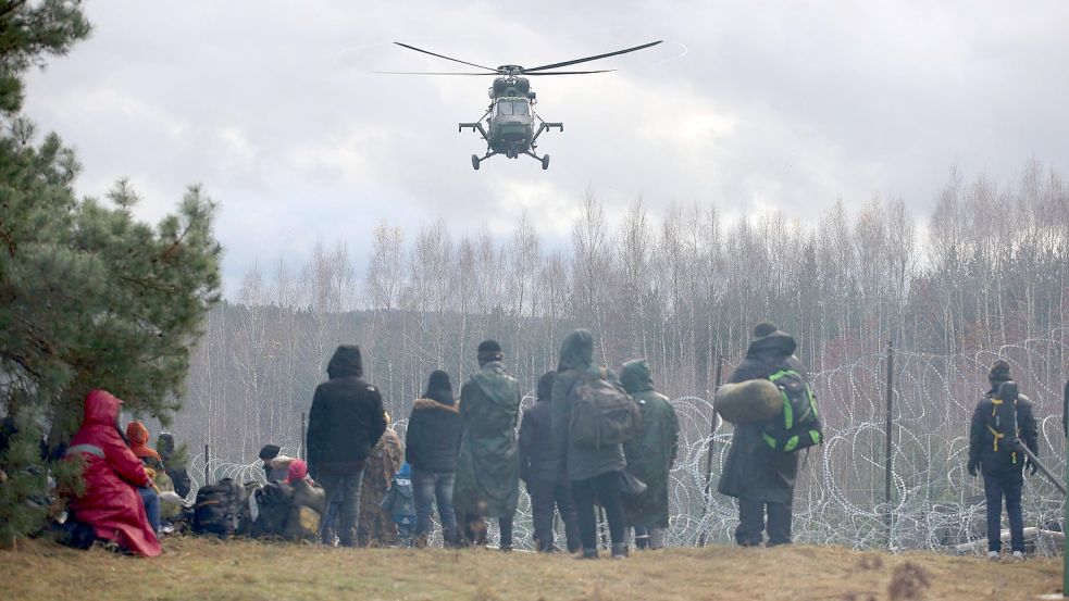 Wie weit eskaliert die Lage noch? Ein polnischer Militärhubschrauber fliegt über eine Gruppe Migranten, die sich an der weißrussisch-polnischen Grenze versammelt haben. Foto: Shcheglov/picture alliance/dpa/BelTA/AP