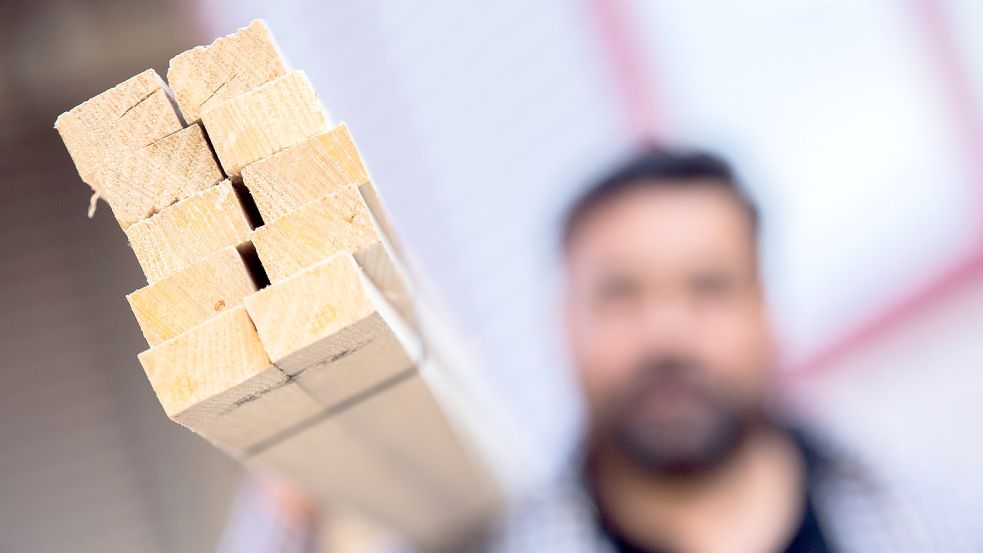 Ein Dachdecker trägt auf seiner Schulter ein Bündel mit Dachlatten. Holz ist derzeit knapp und entsprechend deutlich teurer geworden. In Mecklenburg-Vorpommern hat das Handwerk deshalb schon einen stärkeren Holzeinschlag der Landesforsten gefordert. Foto: Vennenbernd/dpa