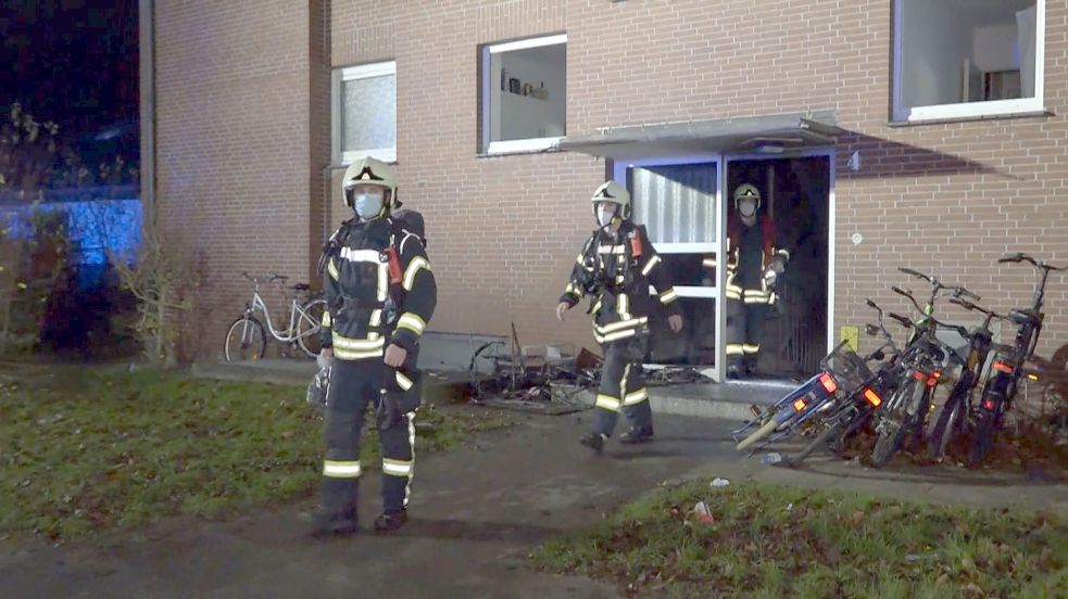 Feuerwehrleute vor dem Mehrfamilienhaus in Wittmund, in dem es in der Nacht zu Sonntag brannte. Foto: André Van Elten/dpa