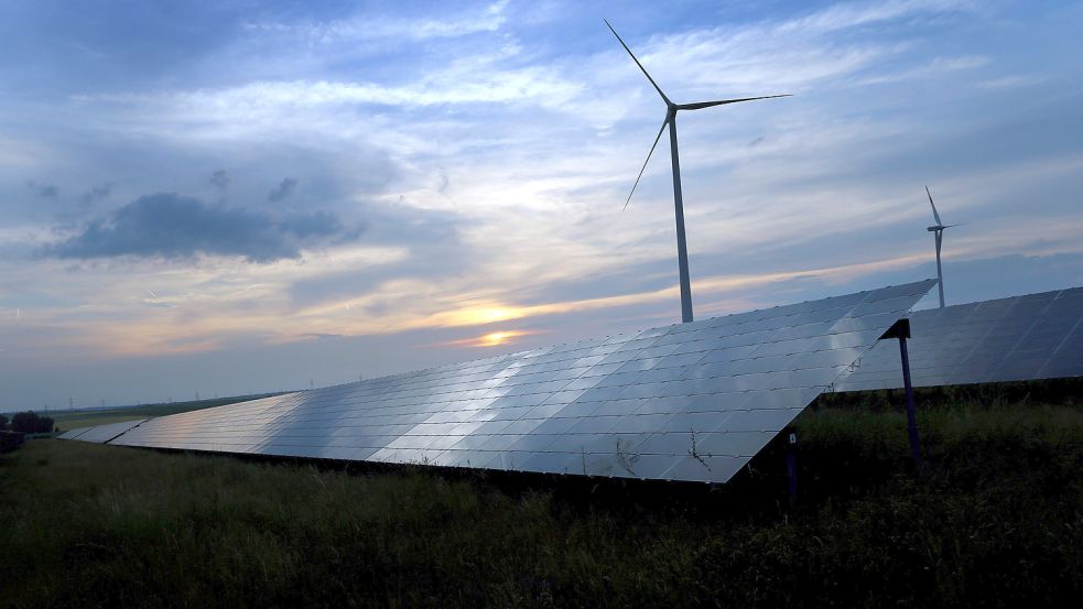 Erneuerbare Energien auf dem Vormarsch: Der Abendhimmel spiegelt sich auf Solarzellen einer vor Windrädern stehenden Solarkraftanlage. Foto: Hildenbrand/DPA