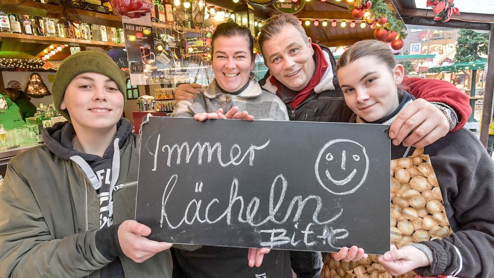Das Lebensmotto der Familie Heine steht auf einer Tafel an ihrem Ausschankbetrieb (von links): Sascha junior, Peggy, Sascha und Sally Heine lächeln, auch wenn sie Sorgen haben. Foto: Ortgies