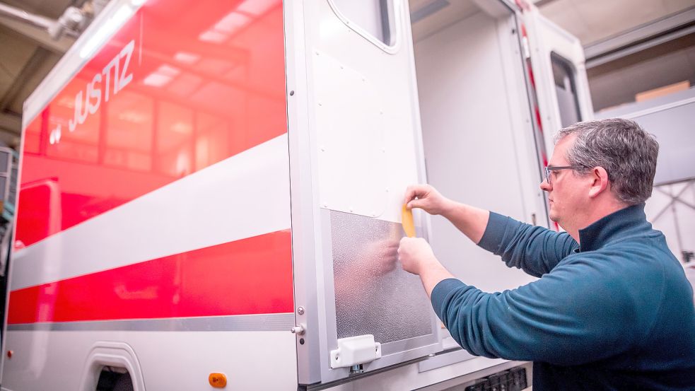 Produktionsleiter Mike Hartmann klebt Türbeschläge eines Transportwagens ab, den Hospimobil für die Justiz fertigt. Foto: Cordsen