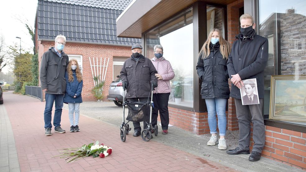 Am Jahrestag der Pogromnacht am 9. November hat Albrecht Weinberg (Mitte)im Jahr 2020 vor dem Wohnhaus seiner Familie in Rhauderfehn seinen Verwandten gedacht. Die Blumen liegen an den Stolpersteinen, die dort verlegt wurden. Links steht Geert Müller, der Rhauderfehner Bürgermeister. Foto: Ammermann/Archiv
