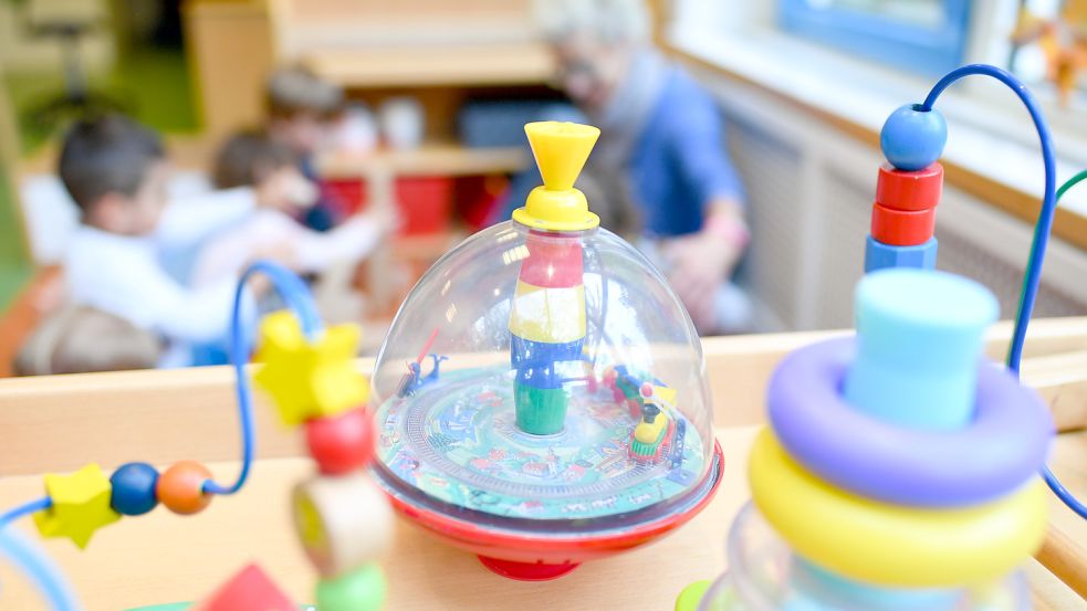 Eine Erzieherin spielt in einer Kita mit Kindern. Im Vordergrund steht Spielzeug. Foto: Anspach/dpa