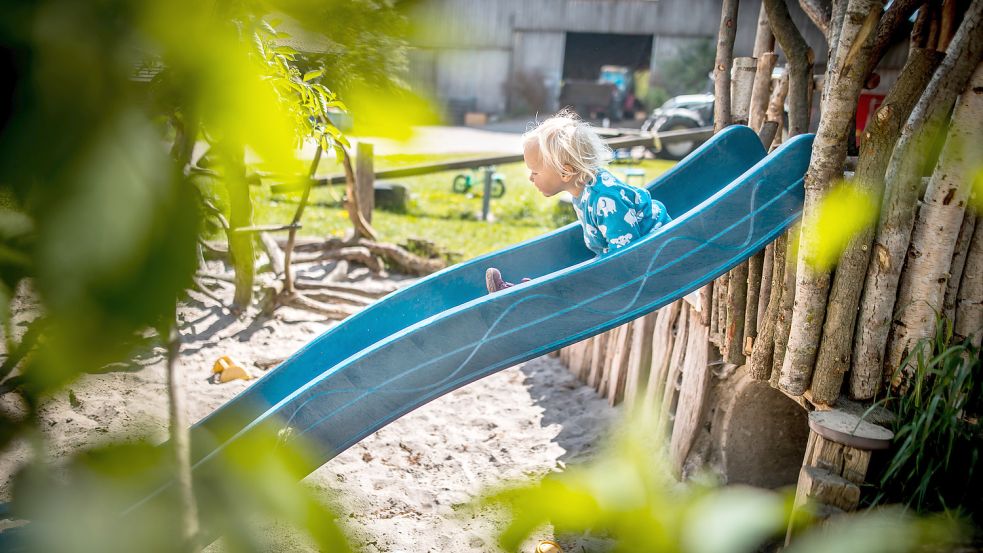 Die kleine Frieda rutscht auf dem hofeigenen Spielplatz. Sieben Kinder leben auf dem Johannshof mit acht Erwachsenen zusammen.