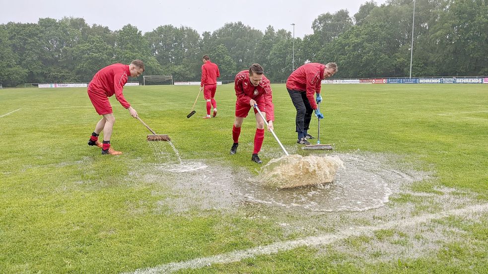 Die Wiesmoorer Spieler gaben alles, um die Wassermassen vom Platz zu bekommen. Doch vergebens: Der Schiedsrichter pfiff die Partie nicht an. Foto: Homes