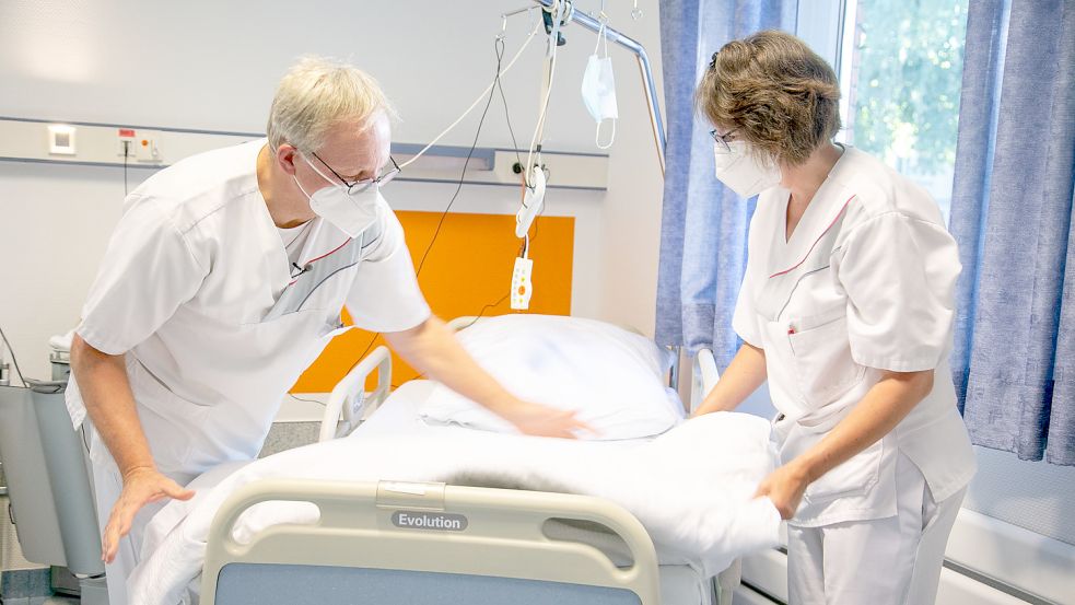 Auch das Bettenbeziehen gehört dazu: Dr. Thomas Günnewig und Gesundheits- und Krankenpflegerin Anke Kunze packen gemeinsam an. Foto: Elisabeth Krankenhaus Recklinghausen/Kristina Schröder