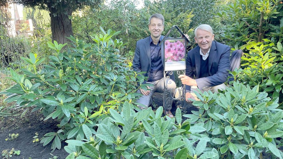 Trauco-Firmenchef und Tullum-Enkel Michael Trauernicht (links) und Jan-Dieter Bruns, Chef der Baumschule Bruns, haben die Info-Tafel zum Tullum-Rhododendron im Garten der Schmiede Striek gesetzt. Foto: Bär