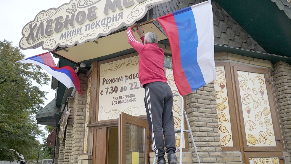 Beginn einer neuen Zeit? Ein Mann hängt die russische Fahne an einem Café in Luhansk auf. Foto: picture alliance/dpa/AP