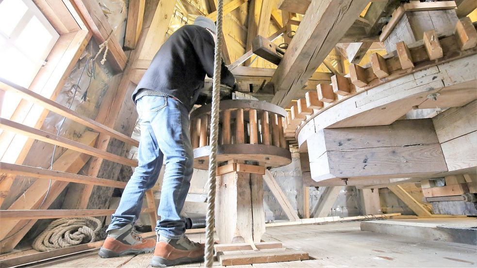 Mahlgang einlegen: Harm Mennen schiebt das Korbrad für den Antrieb des Mahlsteins auf das Stirnrad der Windmühle. Foto: Böning