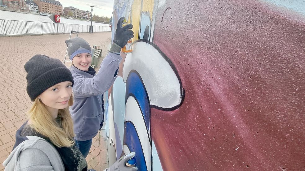 Clara Claus (links) und Kaatje Kellermann sprayen den Leuchtturm auf die Nessemauer. Foto: Bothe