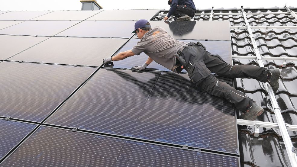 Handwerker montieren auf dem Dach eines Wohnhauses Solarmodule. Foto: Berg/dpa