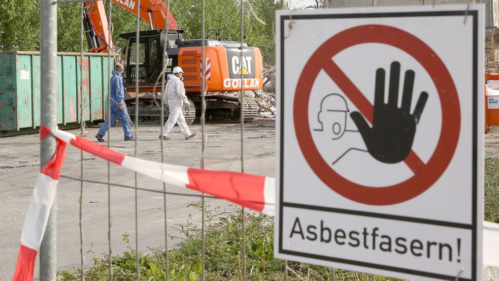 Bei Asbest ist Vorsicht geboten. Dieses Bild zeigt einen Sammelplatz, auf dem asbestbelasteter Schutt lagert. Ein Schild warnt: „Asbestfasern!“ Symbolfoto: Archiv/dpa