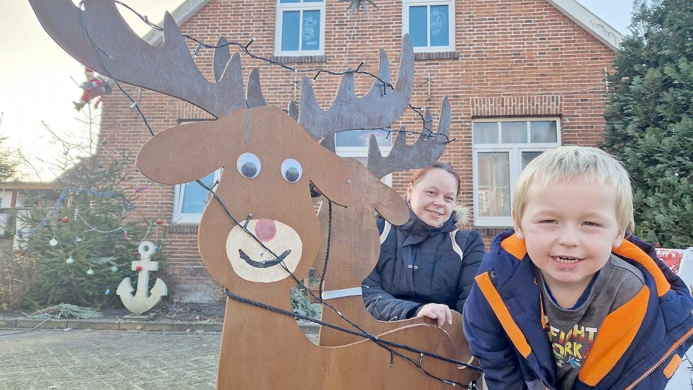 Damian (3) und seine Mutter Patrizia Letas aus Weener freuen sich, wenn die fröhliche Dekoration rund um das Haus auch bei anderen für weihnachtliche Stimmung sorgt. Foto: Gettkowski