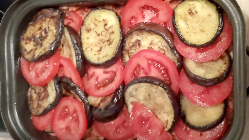 Das Dach aus Auberginen und Tomaten muss noch mit weißer Soße und Käse hitzeversiegelt werden. Foto: Schönig