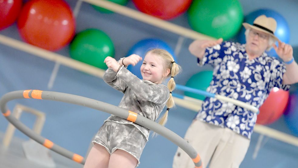 Die große Begeisterung ist Lilly Rehermann bei der generationenübergreifenden Hula-Hoop-Gruppe der TG Wiesmoor ja schon anzusehen. Auch Michael Seewald im Hintergrund ist angetan. Foto: Ortgies