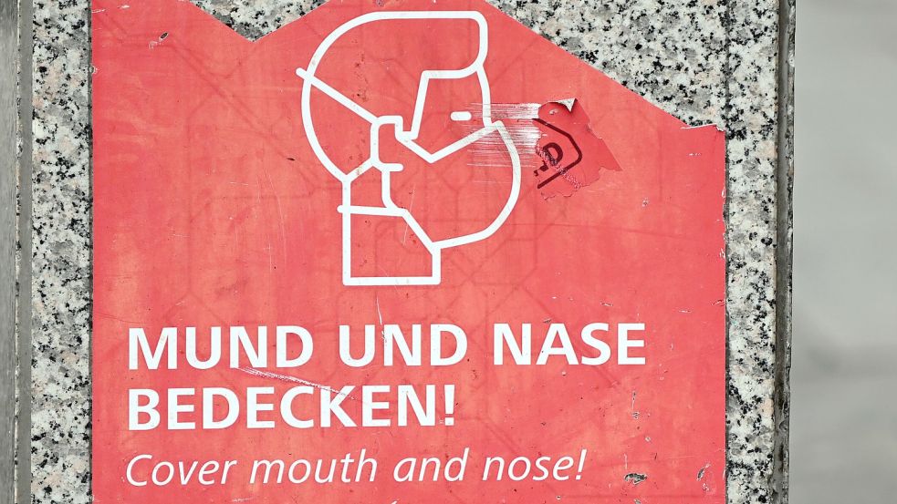 Ein Schild weist auf das Tragen einer Maske hin. Foto: Gambarini/dpa