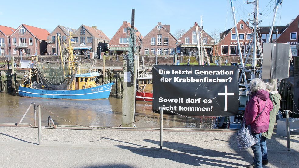 Banner im Neuharlingersieler Hafen erinnern daran, dass die Küstenidylle aktuell täuscht. Foto: Oltmanns