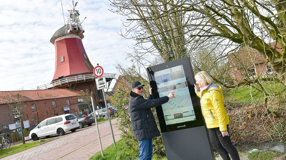 Günther Groll und Beate Schmitt aus Kaiserslautern nutzen die digitale Infotafel, die Touristen über die Auslastung in Greetsiel informieren soll. Foto: Wagenaar