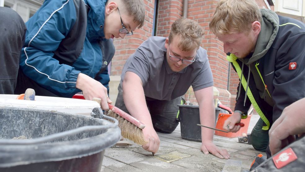 Leon Geiken (links), Sierk Seehusen und Fabian Side von der Berufsfachschulklasse Bautechnik der BBS Aurich II verlegten die Steine der Sternbergs. Foto: Hoppe