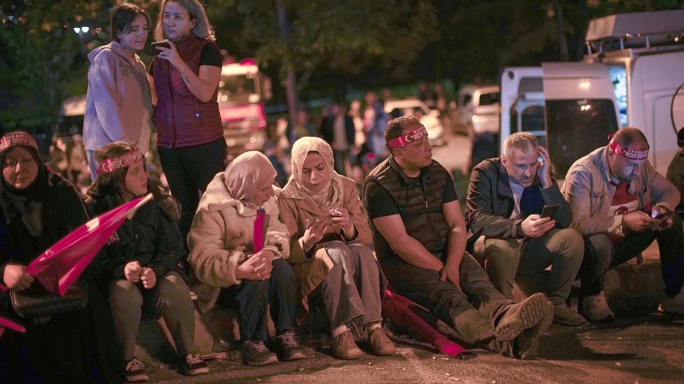 Anhänger des türkischen Präsidenten Erdogan verfolgen die Nachrichten auf ihren Smartphones vor dem Sitz der AKP (Partei für Gerechtigkeit und Entwicklung) in Istanbul. Foto: Seco/AP/dpa