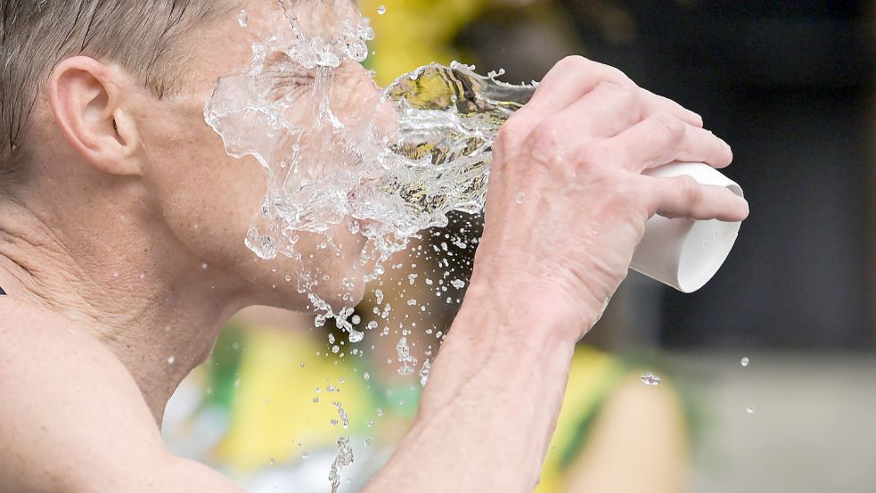 Ein Glas Wasser ins Gesicht – wie bei diesem Marathonläufer – weckt die Lebensgeister. Foto: Gollnow/dpa