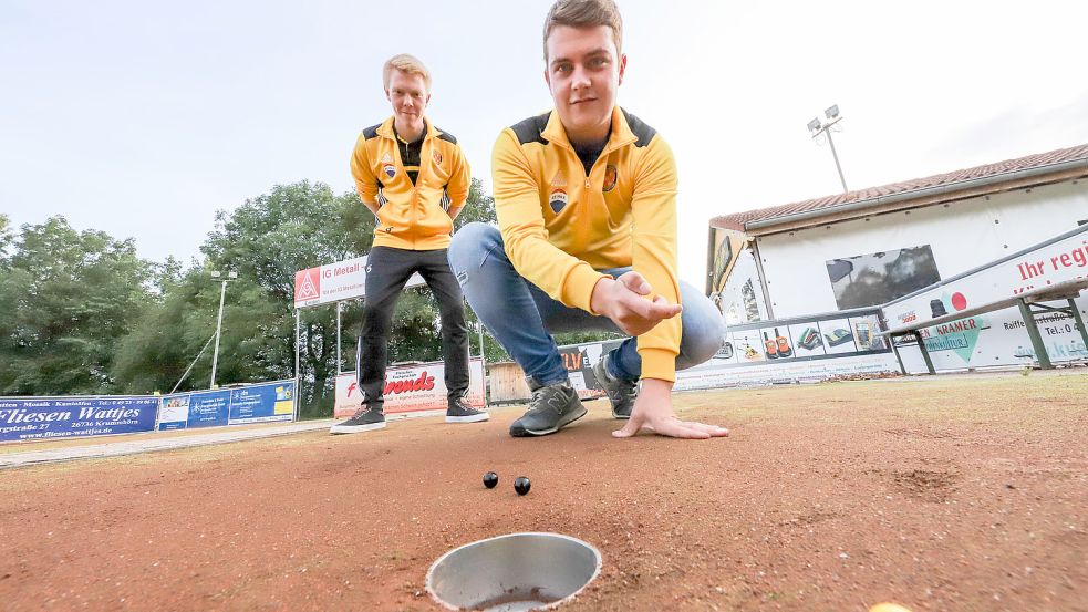 Immo Hillebrand vom SV Jennelt-Uttum zeigt, wie gemurmelt wird. Niko de Haan beobachtet seinen Fußballkollegen dabei, zumindest fürs Foto, ganz genau. Foto: Hock/Archiv