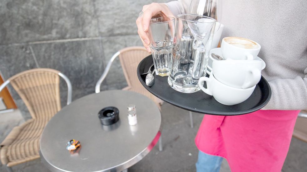 Ein Kellner räumt einen Tisch in einem Restaurant ab. Bundesweit fehlen 65.000 Mitarbeiter in der Gastronomie. Foto: Gollnow/dpa