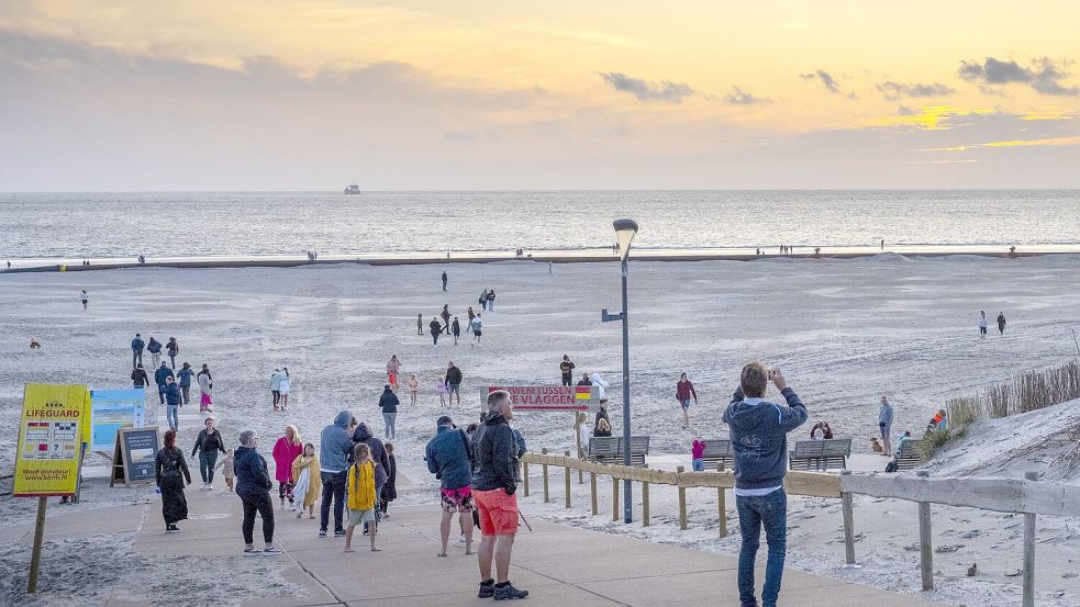 Touristen am Strand von Ameland schauen Richtung See, um den brennenden Frachter zu erblicken. Foto: imago-images/ANP