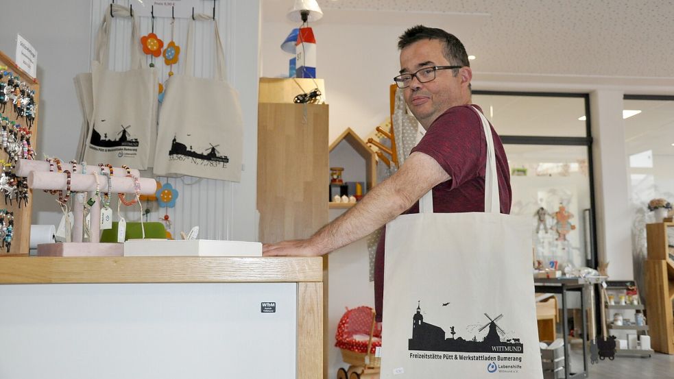 Jürgen zeigt einen der Verkaufsschlager im Werkstattladen Bumerang: die Einkaufstasche mit der Wittmunder Skyline. Foto: Ullrich
