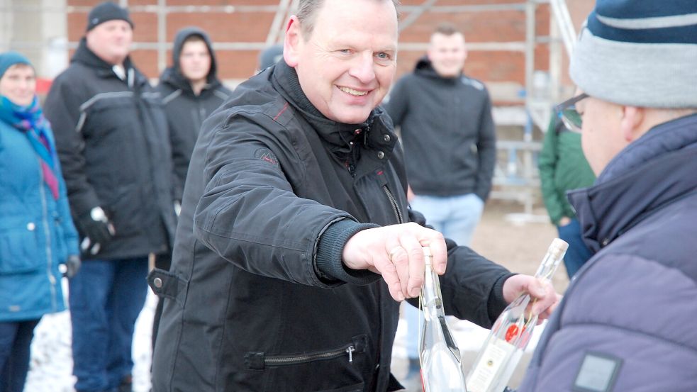 Oberbauleiter Thomas Budden verteilt das Richtwasser – unter anderem an Stadtwerke-Mitarbeiter Olaf Look (rechts). Foto: Ferber