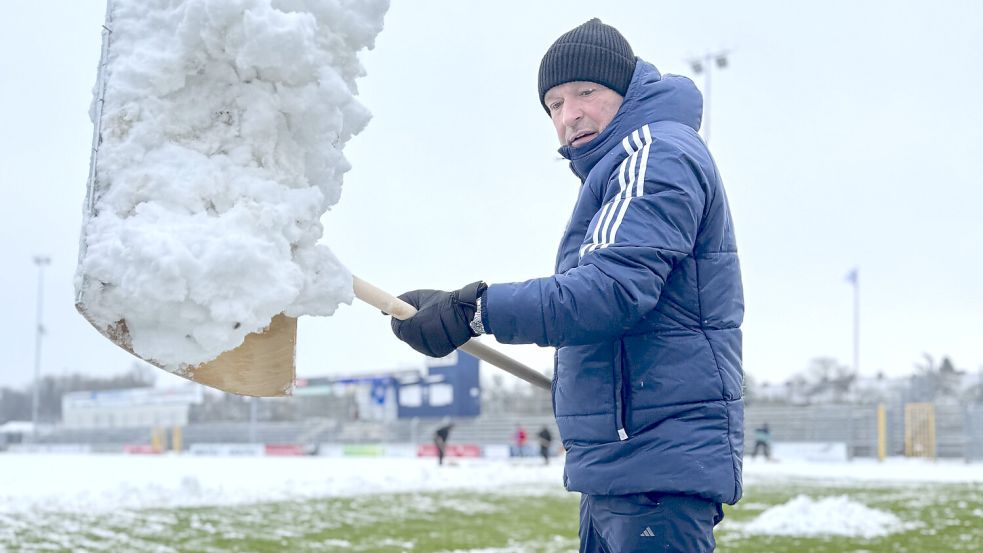 Auch Trainer Stefan Emmerling half mit, den Rasen vom Schnee zu befreien. Fotos: Tobias Bruns/Kickers Emden