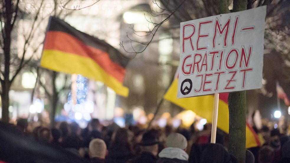 Teilnehmer einer Mahnwache rechter Gruppen stehen im Jahr 2016 mit einem Schild mit einem Logo der identitären Bewegung und der Aufschrift „Remigration Jetzt“ vor dem Bundeskanzleramt. Foto: von Jutrczenka/picture alliance/DPA/Archiv