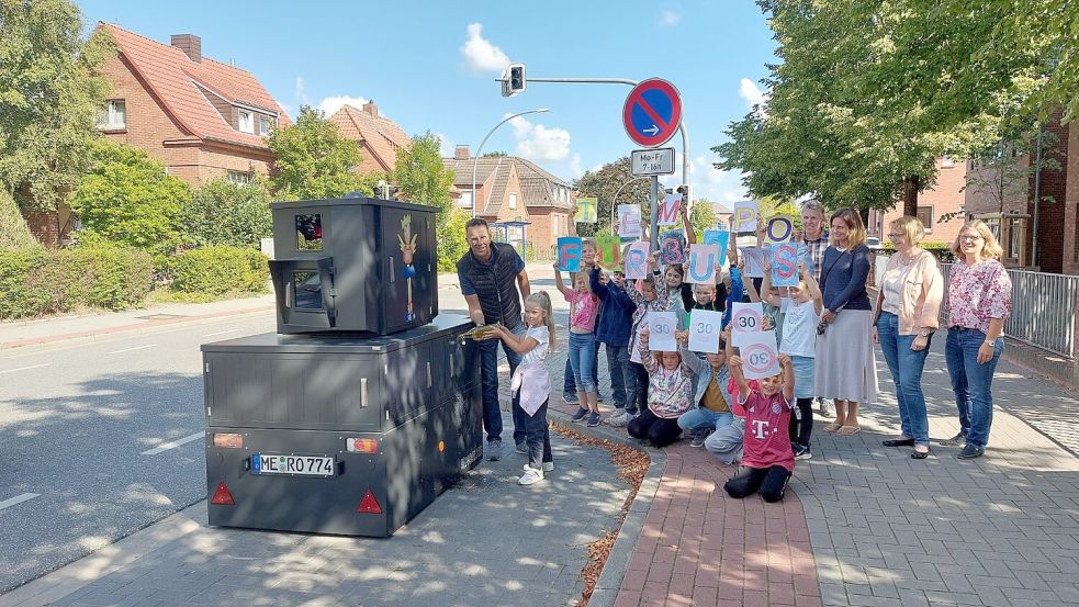 Im September 2022 wurde der Blitzer Engelke feierlich vor der Grundschule Wolthusen mit Meerwasser getauft. Die Kinder halten Schilder hoch, auf denen steht "Tempo 30 für uns". Das Kennzeichen von Engelke ist mittlerweile ein Emder. Foto: Hanssen/Archiv