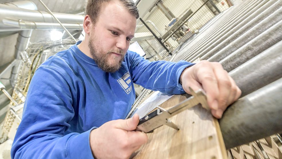 Nils Engels kontrolliert die richtige Positionierung der Löcher eines Möbelteils. Foto: Ortgies