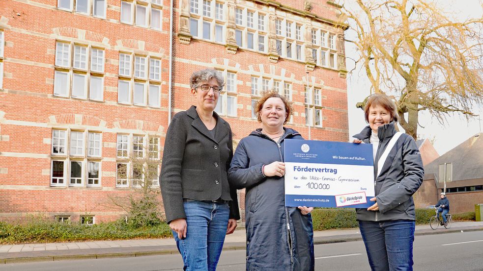 Der Altbau des Ubbo-Emmius-Gymnasiums stammt aus dem Jahr 1909 und muss saniert werden. An den Kosten von mehr als einer Million Euro beteiligt sich die Deutsche Stiftung Denkmalschutz mit 100.000 Euro. Den Scheck übergab Ortskuratorin Sabine Jetzlaff (Mitte) an Schulleiterin Ute Wieligmann (rechts) und die Erste Kreisrätin Jenny Daun. Foto: Lüppen