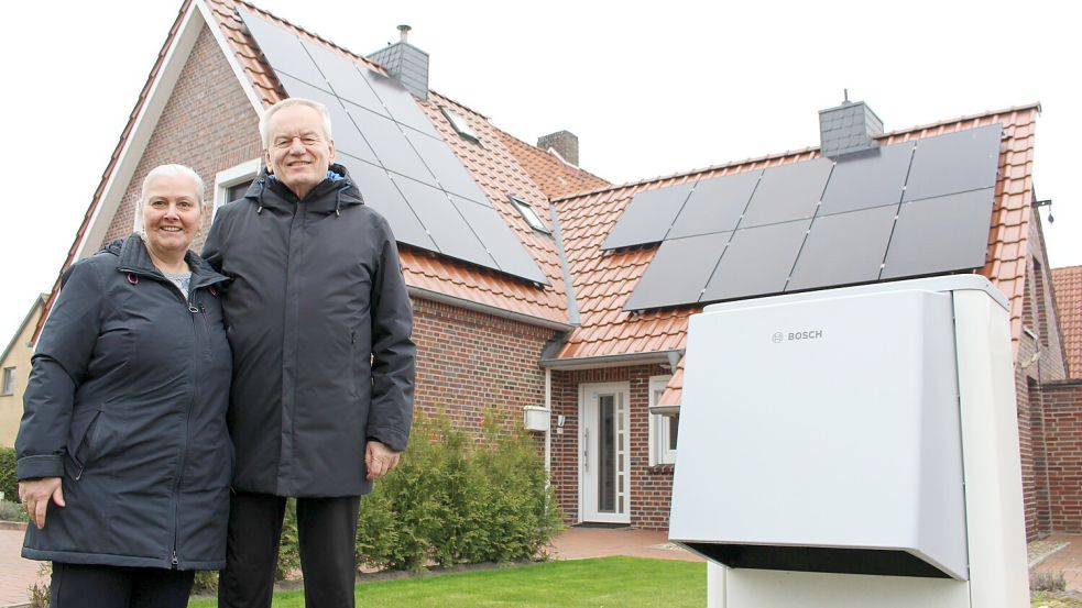Susanne und Lothar Rust vor ihrem energetisch umgerüsteten Haus in Wittmund. Im Vordergrund die Wärmepumpe im Garten. Foto: Oltmanns
