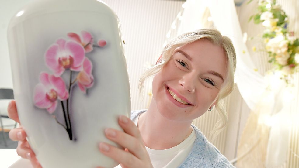 Marie Janssen zeigt eine Urne mit einem Blumenmotiv. Foto: Ortgies