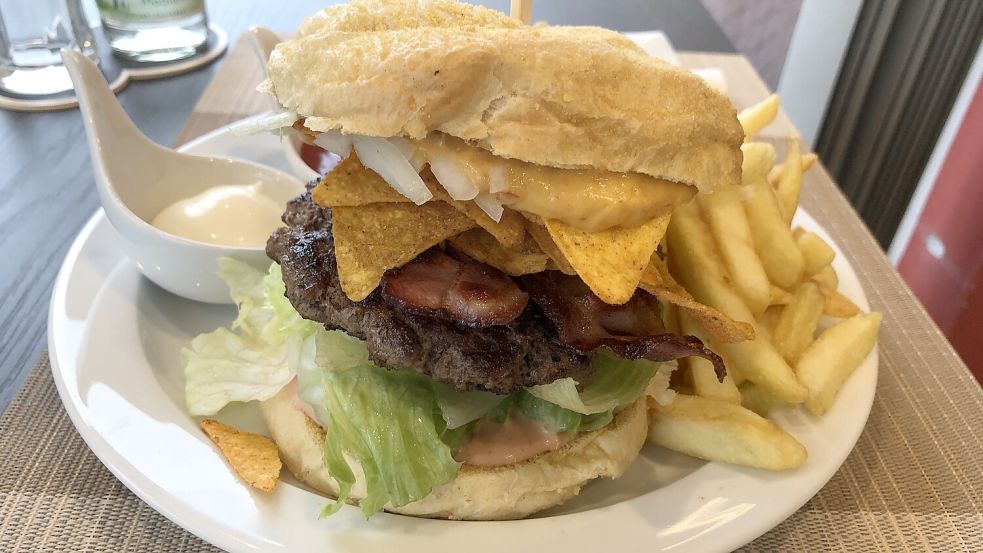 So sieht er aus, der Nacho-Burger in Hannis Imbiss. Im Hintergrund: eine große Portion Pommes mit Mayo und – etwas versteckt hinter dem Burger-Turm – Ketchup. Foto: Leonhard