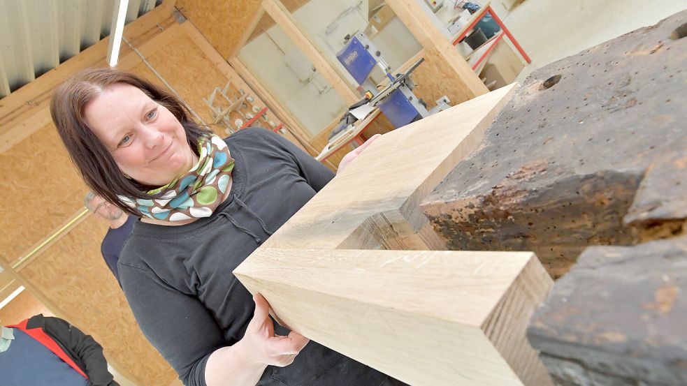 Mirja Harms zeigt, wie ein neues Stück Holz an den alten Webstuhl angepasst wurde. Das Holz wird noch so bearbeitet und gebeizt, dass man kaum einen farblichen Unterschied sieht. Foto: Ortgies