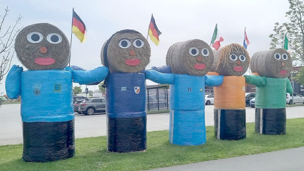 Am Ortseingang in Neuharlingersiel begrüßen die Strohballen-Figuren mit den Trikots, Logos und Fahnen der teilnehmenden Boßel-Verbände die Friesensportler. Auf dem Parkplatz dahinter startet Donnerstag der Festumzug. Foto: Siemens