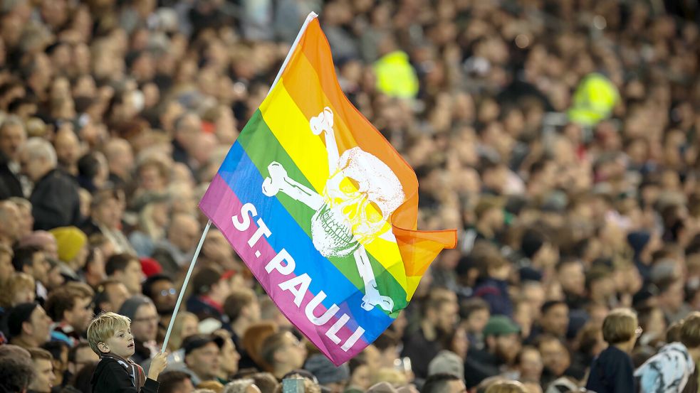 Fans von Sankt Pauli feiern ihre Mannschaft. Die Totenkopffahne wird hier in Regenbogenfarben zum Symbol von Akzeptanz und Toleranz. Foto: Charisius/dpa