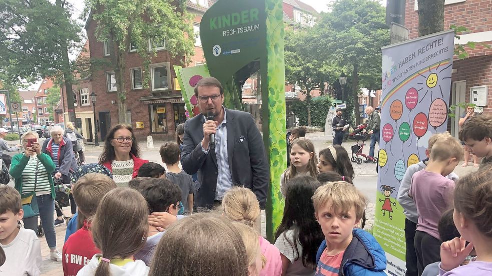 Oberbürgermeister Tim Kruithoff (am Mikrofon) und die Vorsitzende des Emder Kinderschutzbundes, Regina Meinen (links neben Kruithoff) fordern die Aufnahme der Kinderrechte ins Grundgesetz. Foto: H. Müller