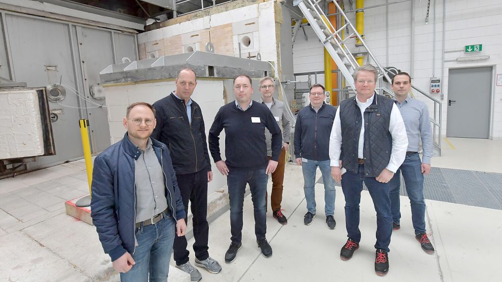Andreas Dirksen (Leiter Personalmanagement, von links), Johann Stöhr (Prokurist und Verwaltungsleiter), Rainer Dornbusch (Leiter Brandschutz- und Entrauchungstechnische Systeme und Komponenten), Arne Dahms (Leiter Lufttechnische Systeme und Komponenten), Jürgen Wildeboer (Geschäftsführer), Arne Bröske (Produktionsleiter) und Tobias Meimberg (Leiter Entwicklungslabore und Prototypenservice) stehen vor dem Brandprüfofen. Foto: Ortgies