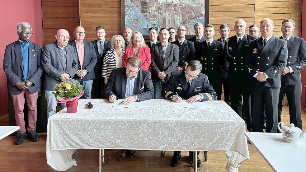 Unterzeichnet: Oberbürgermeister Tim Kruithoff und Marine-Kapitän Sebastian Lehmann-Devall besiegeln die Patenschaft für die Korvette Emden vor Zeugen aus Rat und Mannschaft. Foto: Schuurman